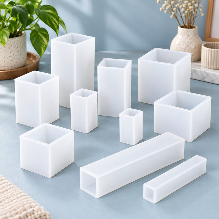 A set of white translucent rectangular silicone plant pots in various square and long tube shapes, arranged on a light blue surface with decorative plants in the background.