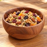 Acacia serving bowl filled with grains and dried fruit.