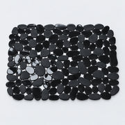 A rectangular black pebble mat made of smooth, glossy black stones arranged in a grid pattern on a light gray background.