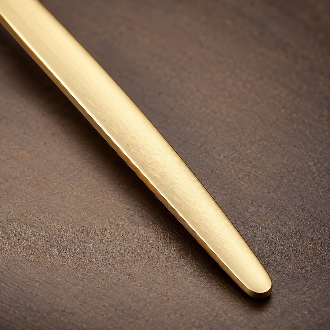 Close-up of a gold fork fine brushed handle finish and smooth edge.