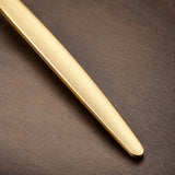 Close-up of a gold fork fine brushed handle finish and smooth edge.
