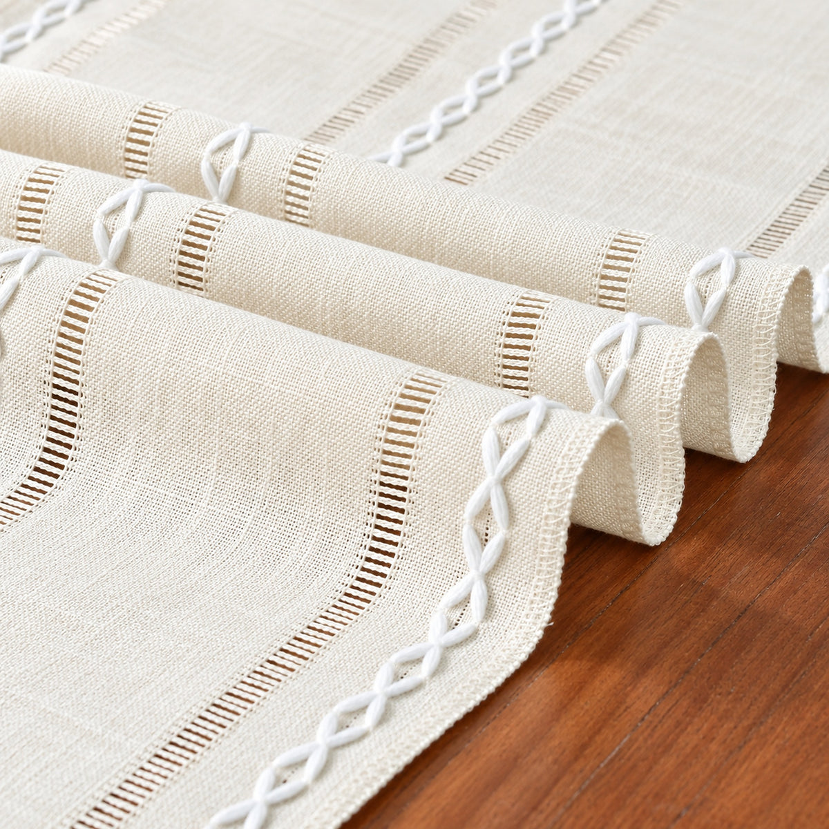 Close-up of ivory woven fabric, openwork hemstitch and white looped embroidery.