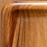 Macro of the wood tray rounded corner, raised rim and natural grain.