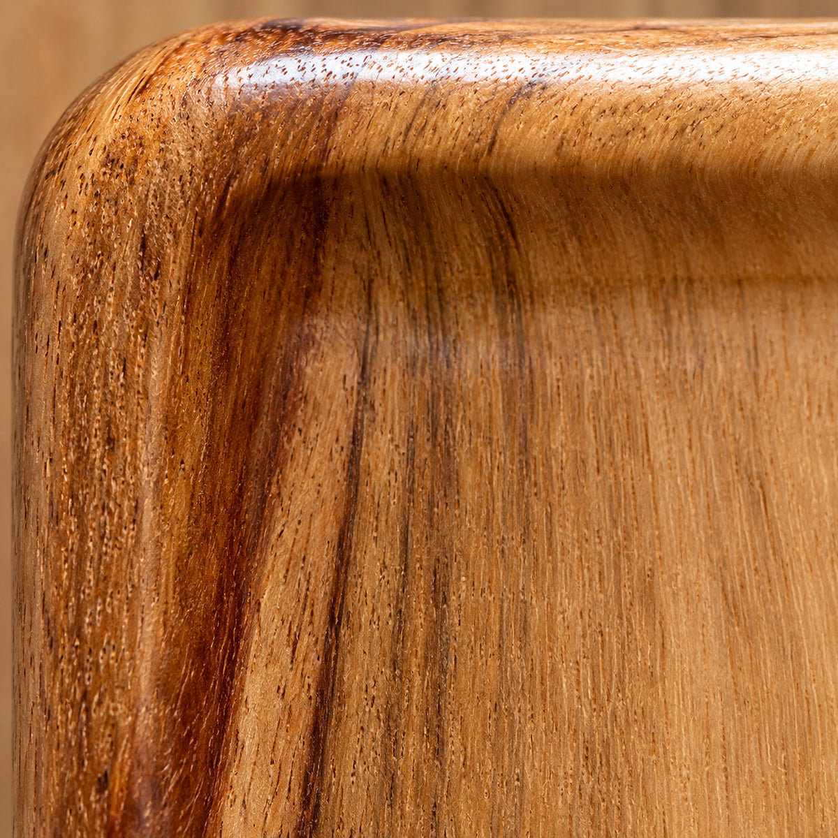 Macro of the wood tray rounded corner, raised rim and natural grain.