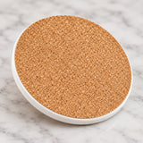 Cork backing and thin ceramic edge of one round coaster.