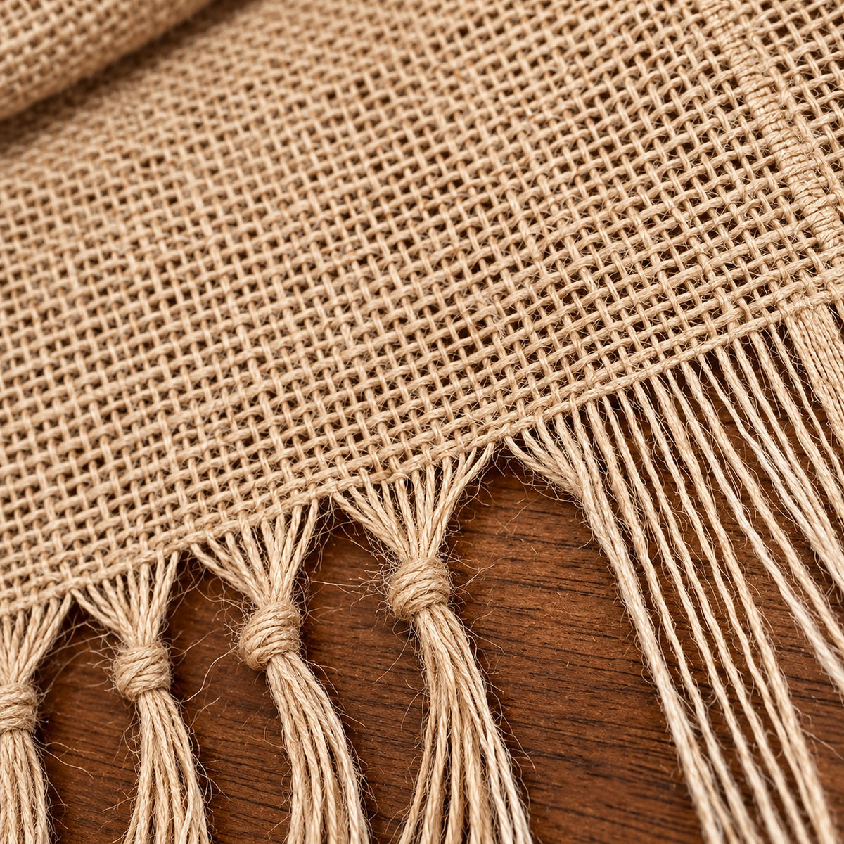 Close-up of coarse woven jute fibers and stitched fringe junction.