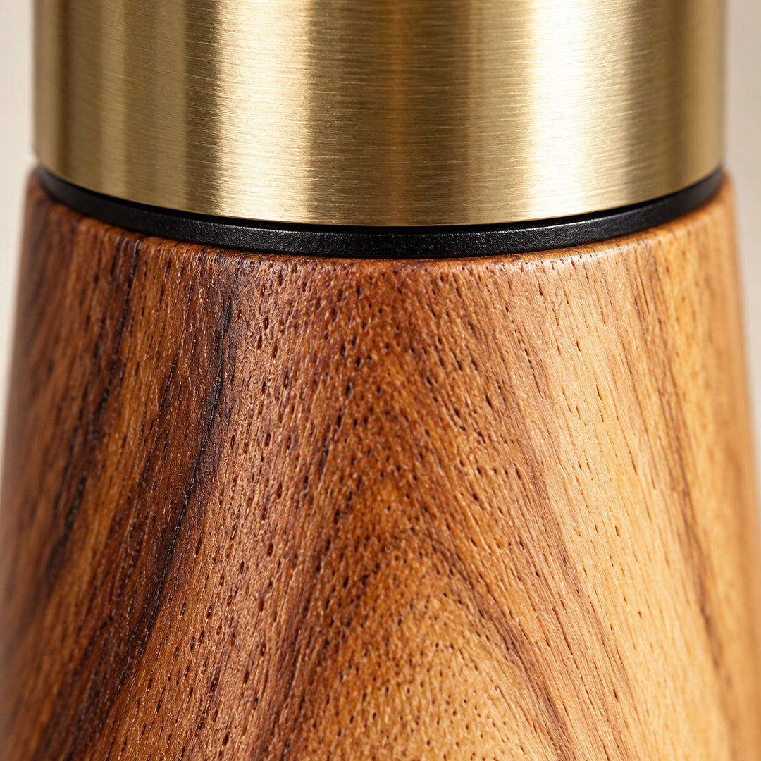 Close-up of acacia woodgrain, the black joining ring and gold-colored stainless steel.
