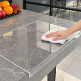 Clear acrylic cutting board being wiped with a damp cloth on a countertop.