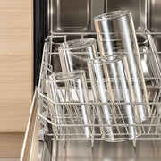 Four clear glass drinking cups arranged on a stainless steel dishwasher rack inside an open dishwasher.
