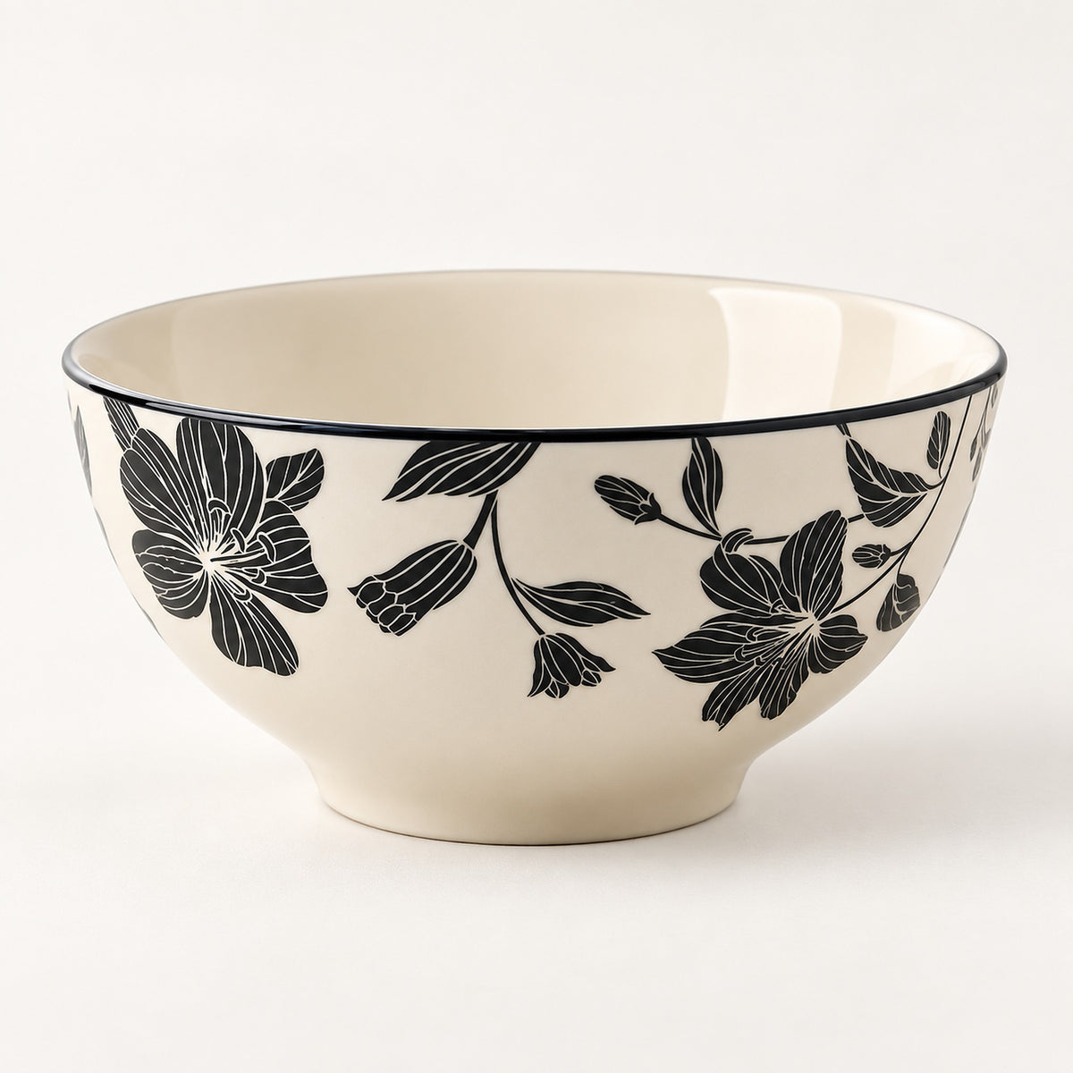 An off-white ceramic bowl featuring a black floral pattern on the exterior and a thin black rim, photographed against a clean white background.