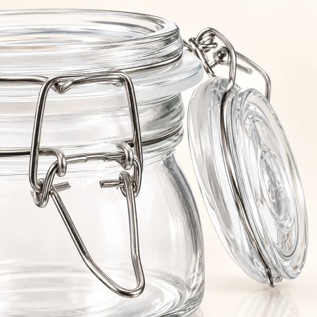 Clear glass jar with a silver metal clamp lid and glass seal, shown close up on a light beige background.