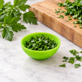 Mini silicone bowl holding chopped herbs for food prep.