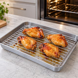 Roasted chicken pieces on the seated rack with cooking drips collected in the tray.