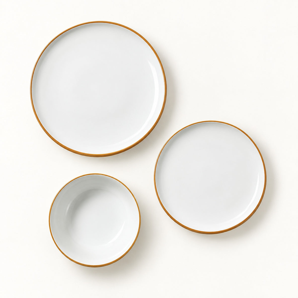 Three-piece white ceramic dinnerware set with a thin gold rim, including a large plate, a medium plate, and a small bowl, arranged on a clean white background.