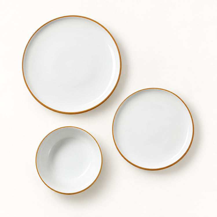 Three-piece white ceramic dinnerware set with a thin gold rim, including a large plate, a medium plate, and a small bowl, arranged on a clean white background.