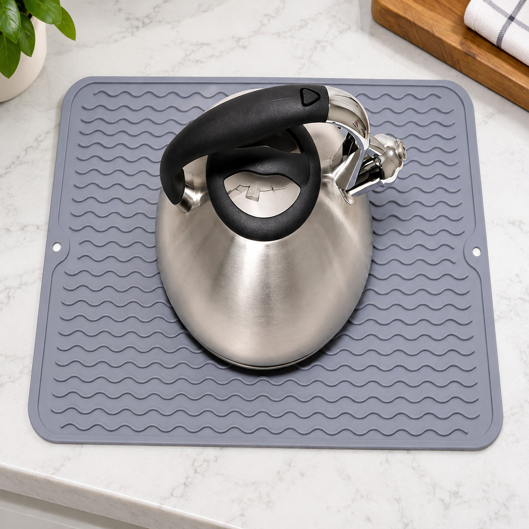 Gray silicone mat beneath a stainless steel kettle.