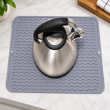 Gray silicone mat beneath a stainless steel kettle.