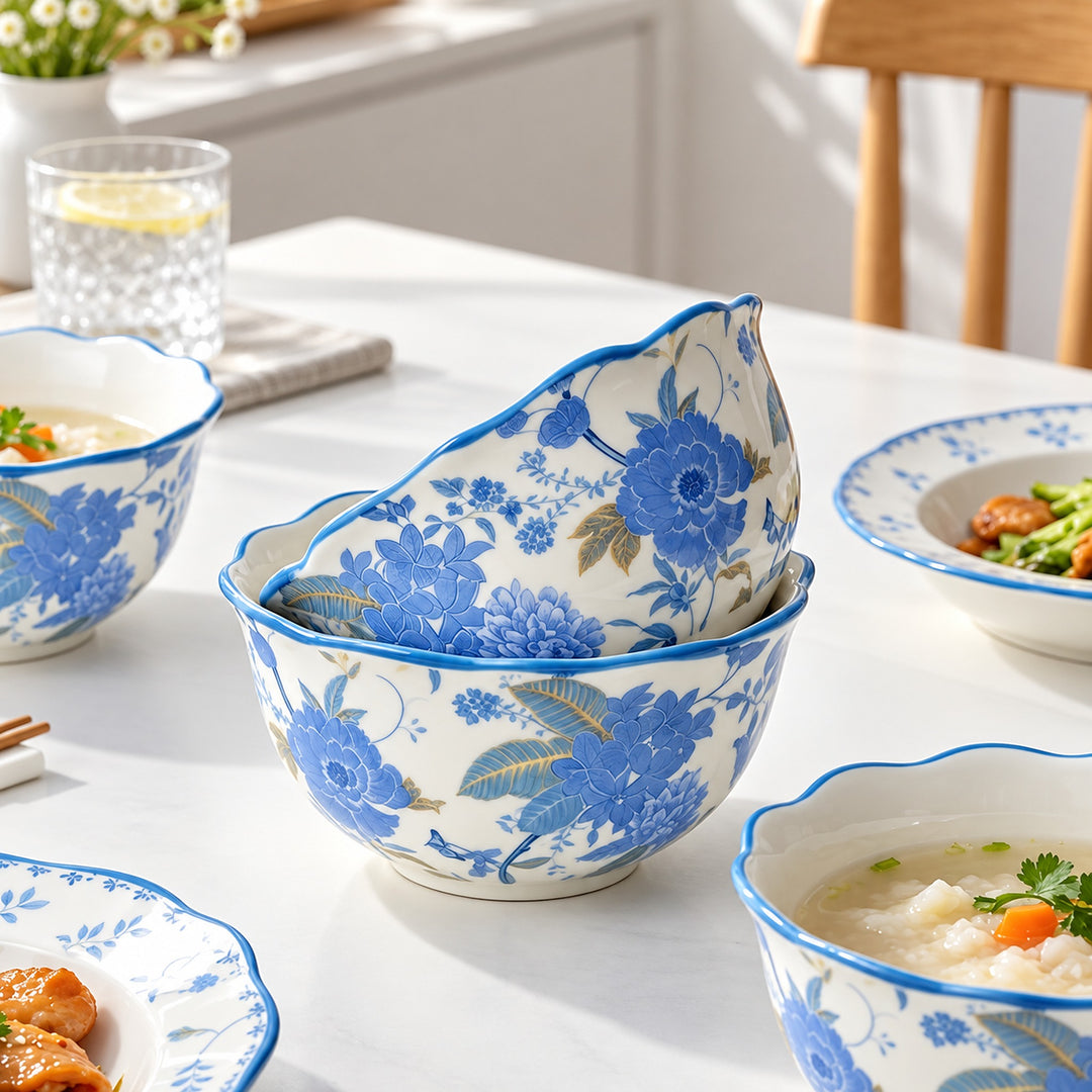 Blue and white floral ceramic bowls arranged on a dining table, with soup and food visible in some bowls, in a bright indoor setting.