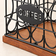 Close-up of a black metal coffee organizer with an oval sign reading COFFEE and a wooden base, shown on a light beige surface.