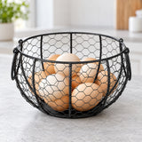Black wire egg basket holding eggs on a kitchen counter.