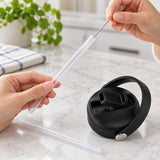 Cleaning one clear straw with included brush; spare straw and black lid nearby.