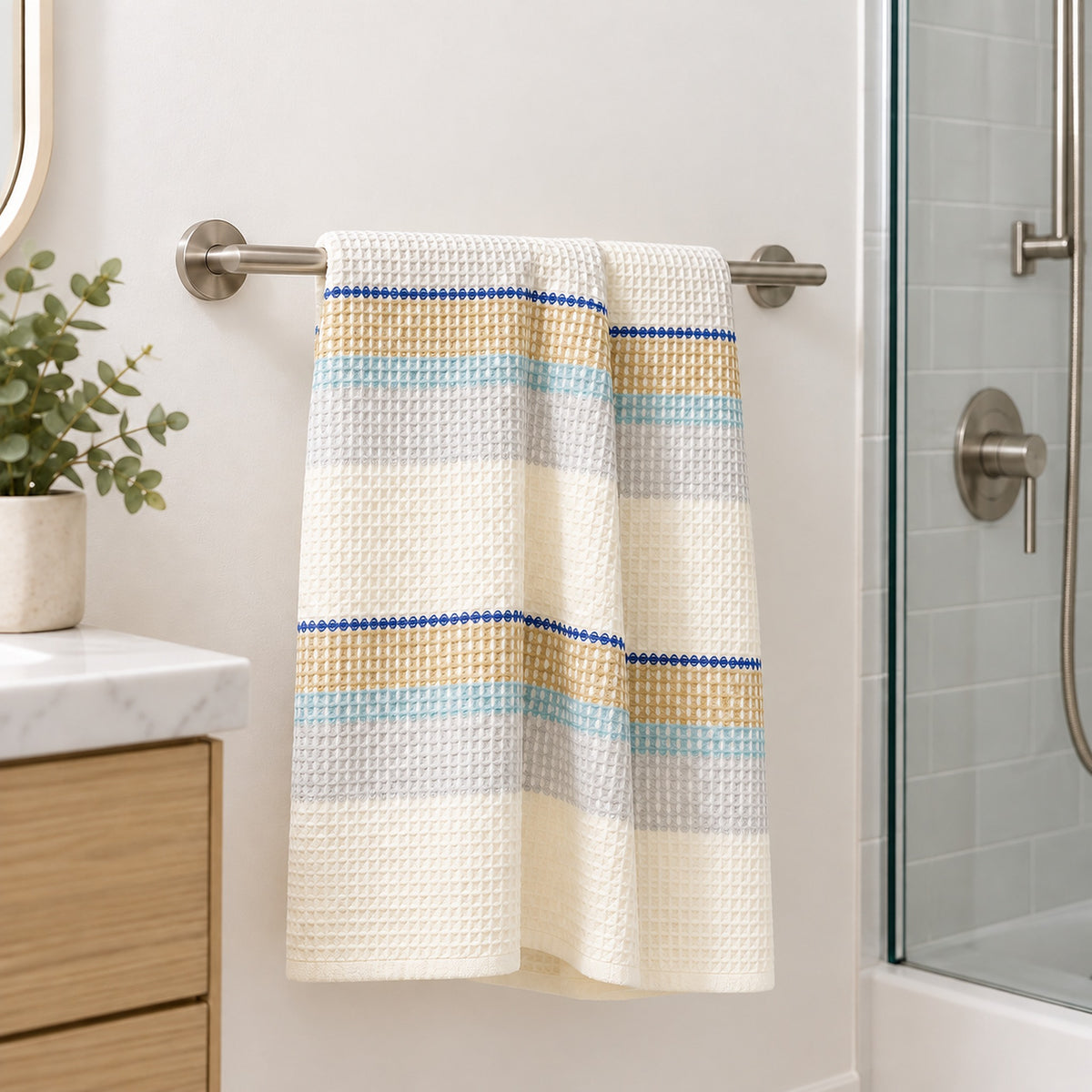 One blue striped cotton waffle towel hanging beside a shower; fixtures not included.