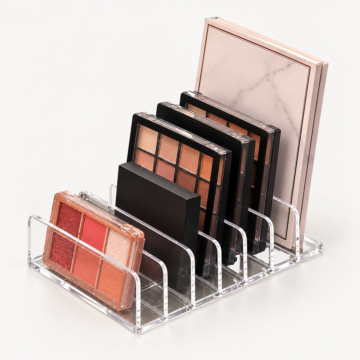 A clear acrylic makeup organizer stand holding several eyeshadow palettes in different colors and sizes against a clean white background.
