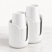 Two white ribbed cup holders on a light marble surface against a white background, each holding a stack of white cups.