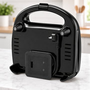 A black electric kettle with a built-in handle and power cord, shown on a white marble countertop with a blurred kitchen background.