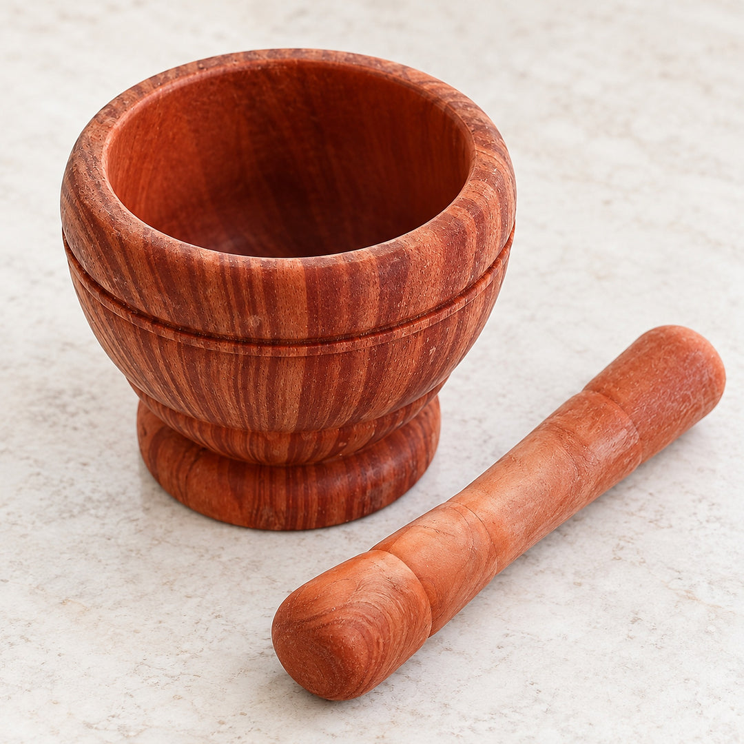Dark brown patterned mortar with its matching pestle beside the empty bowl.