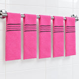 Five pink exfoliating mitts spaced along a bathroom rail between uses.