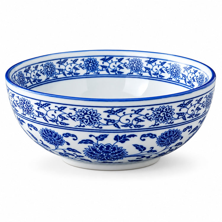 A white ceramic bowl decorated with a classic blue floral and vine pattern, shown against a plain white background.