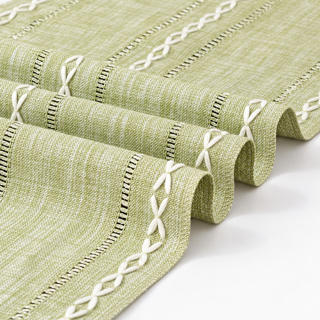 Close-up of sage-green woven runner and white embroidered detail.