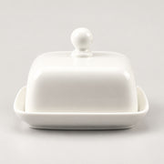 A white ceramic butter dish with a matching lid featuring a round knob and a shallow base, photographed on a clean light gray background.