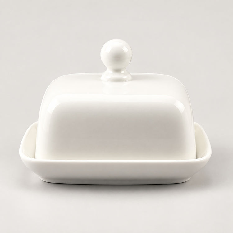 A white ceramic butter dish with a matching lid featuring a round knob and a shallow base, photographed on a clean light gray background.