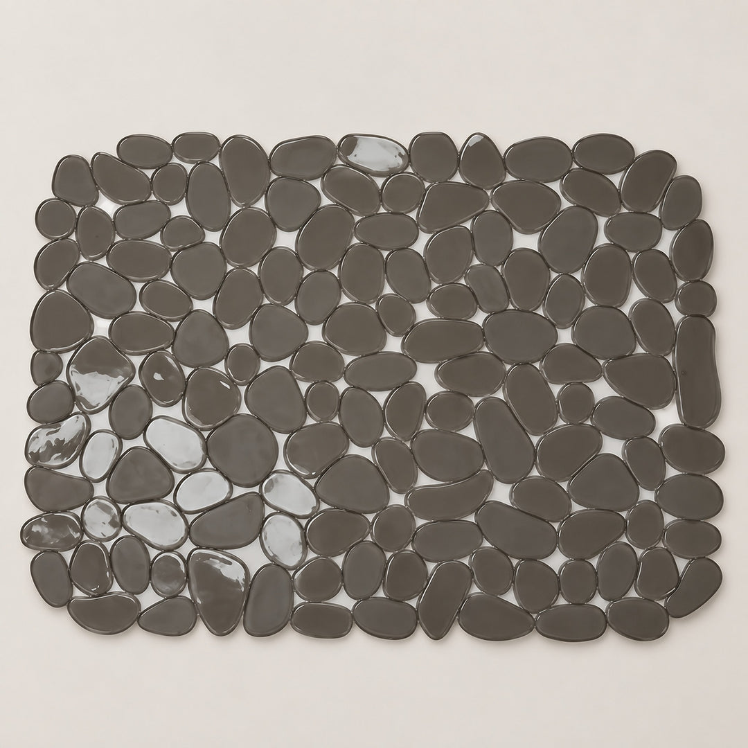 A rectangular bath mat made of smooth, dark gray pebble-shaped tiles, shown from a top-down view on a light beige background.