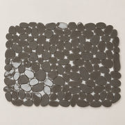A rectangular bath mat made of smooth, dark gray pebble-shaped tiles, shown from a top-down view on a light beige background.