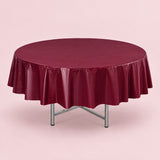 One wine red disposable PVC tablecloth draped over a round table.