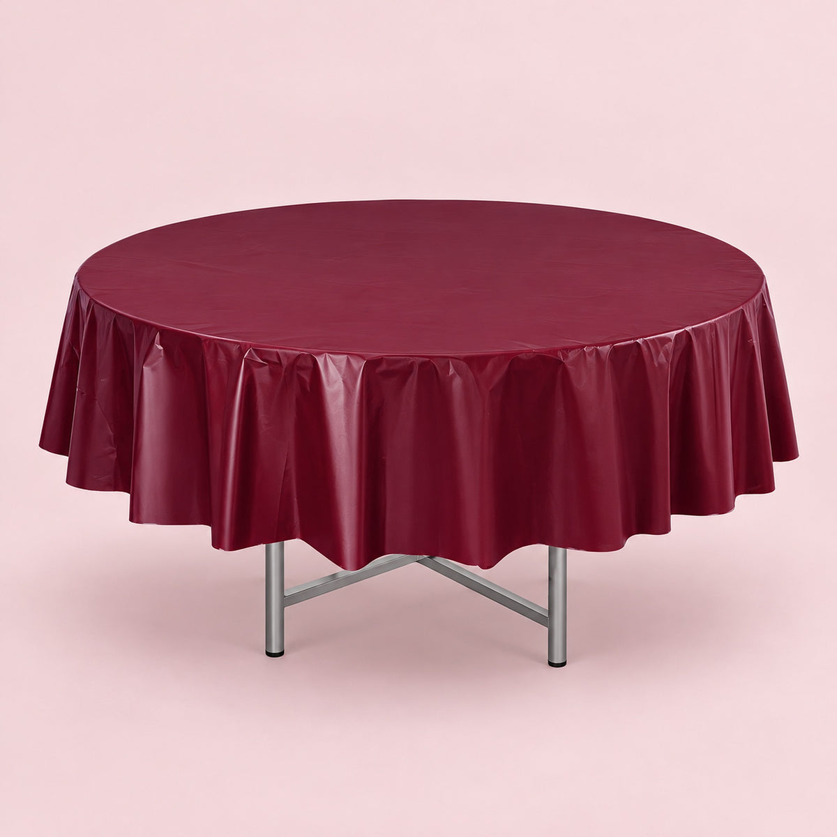 One wine red disposable PVC tablecloth draped over a round table.