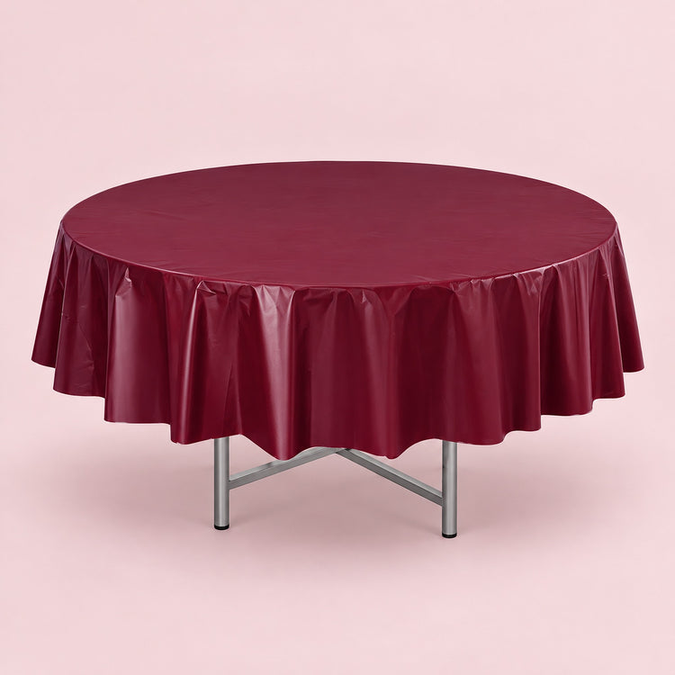 One wine red disposable PVC tablecloth draped over a round table.