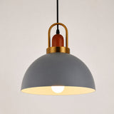 A modern pendant light with a matte gray dome shade, a warm brass-colored metal top frame, and a visible glowing light bulb inside.