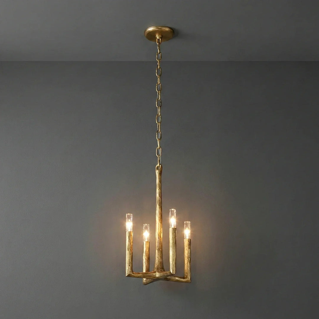 A rustic gold branch-style chandelier with four candle-shaped bulbs, suspended from a ceiling against a dark gray wall.