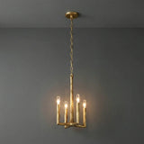 A rustic gold branch-style chandelier with four candle-shaped bulbs, suspended from a ceiling against a dark gray wall.