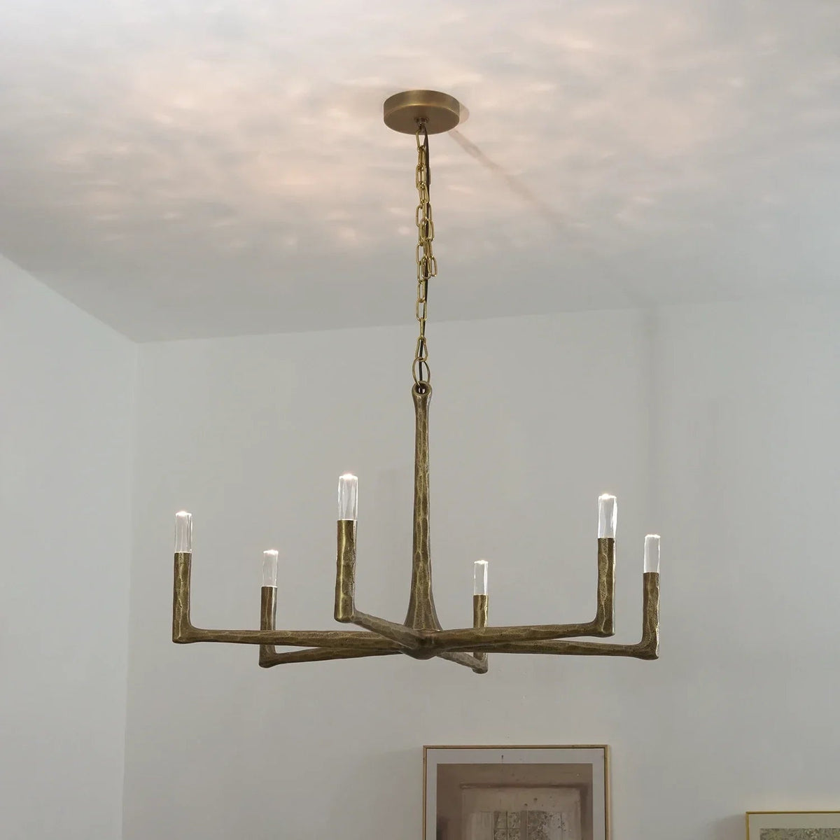 Bronze chandelier hanging from a ceiling with a neutral background