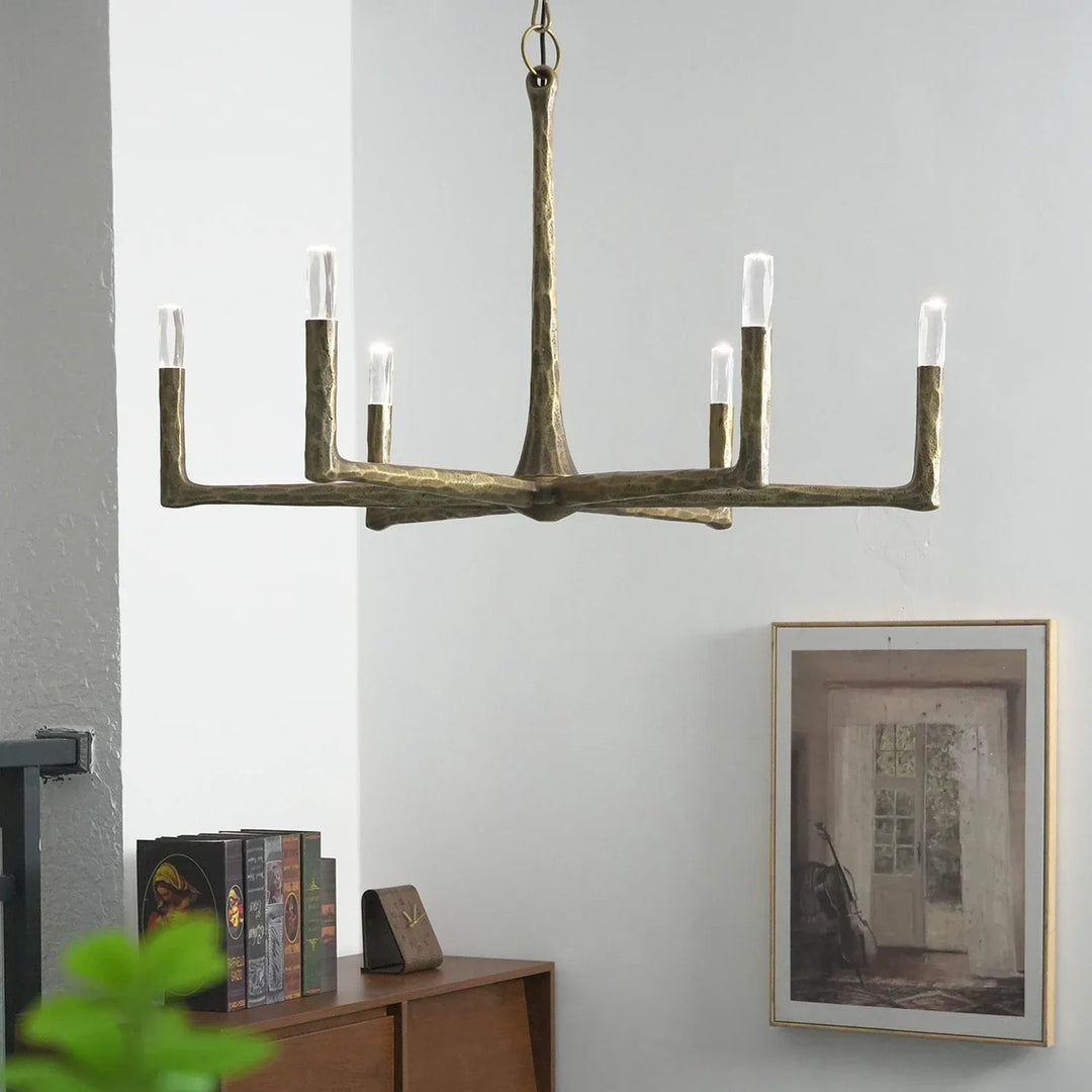 Decorative chandelier hanging in a room with a wall painting and books on a shelf.