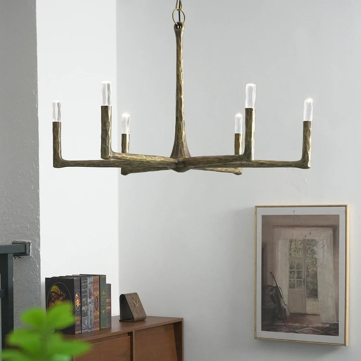 Decorative chandelier hanging in a room with a wall painting and books on a shelf.