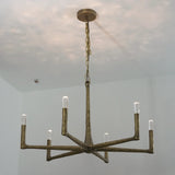 A rustic six-light chandelier with a distressed bronze finish, suspended from a ceiling by a chain, shown in a room with white walls.
