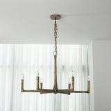 A rustic six-light chandelier with a weathered bronze finish hangs from a chain and ceiling canopy in a bright room with white curtains.