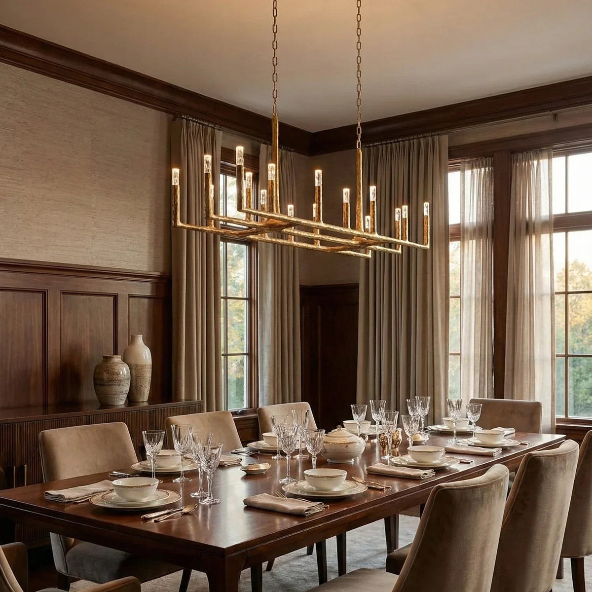 Dining room with a large wooden table set for dinner, elegant chandelier, and large windows.