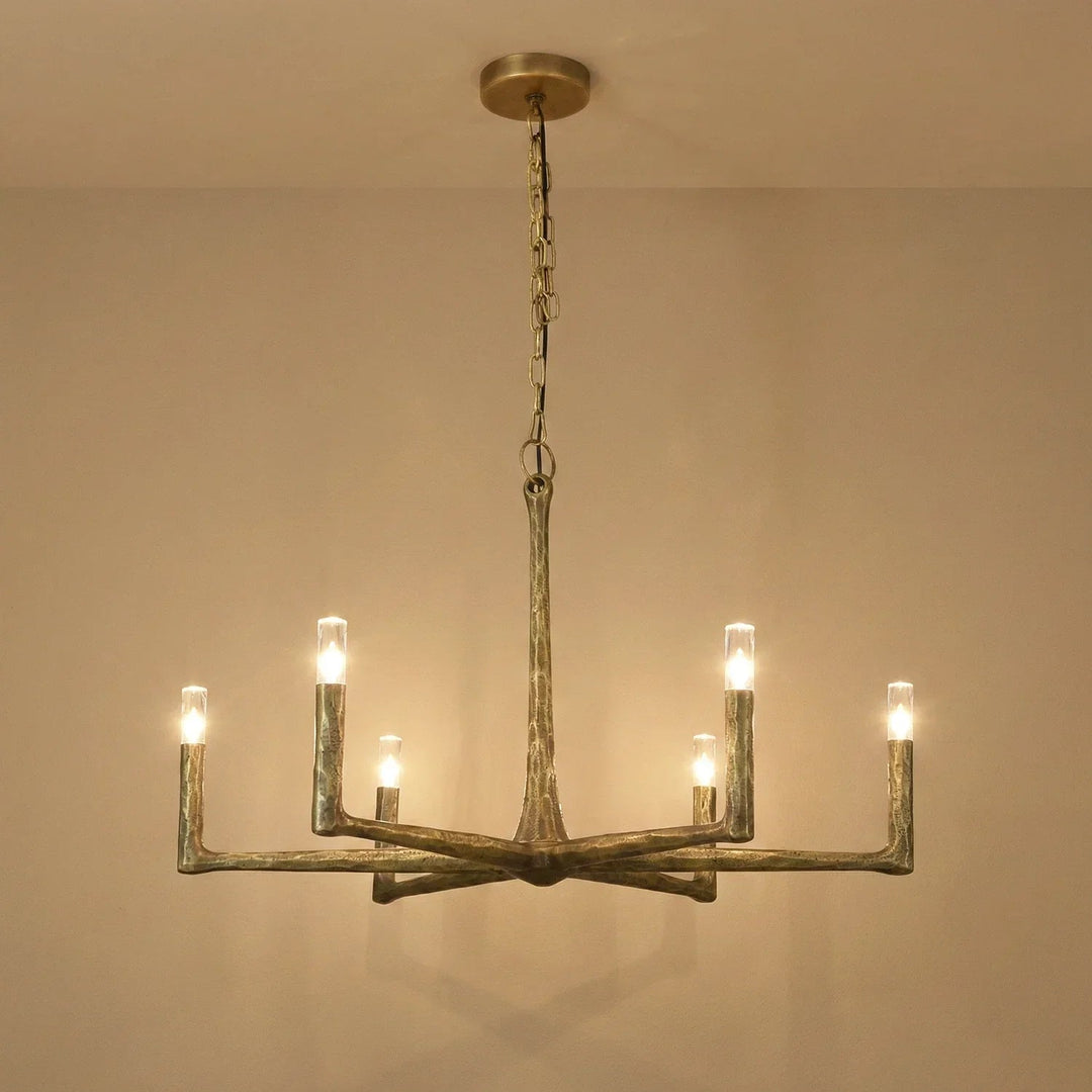 A rustic six-light chandelier with a weathered metal finish, suspended from a ceiling by a chain, shown against a plain beige wall.